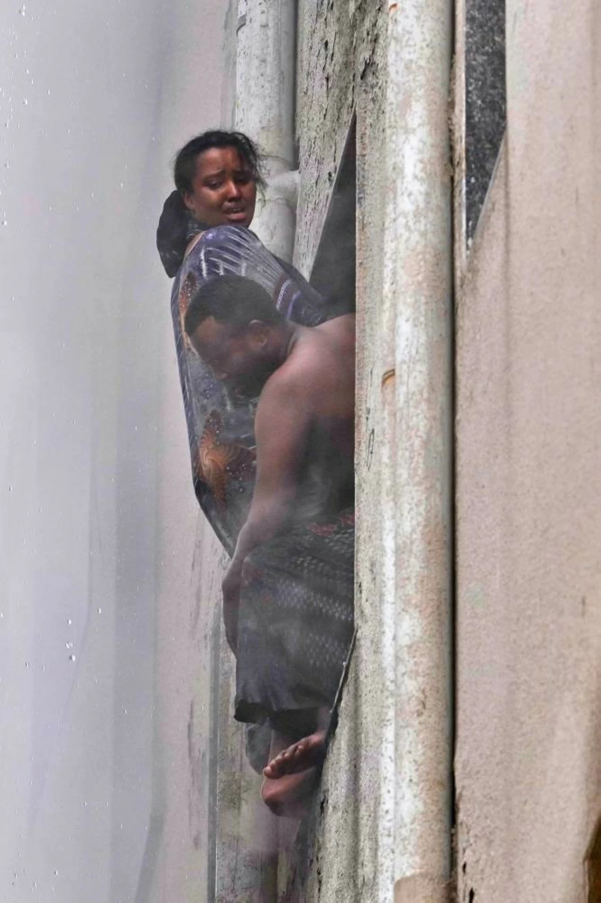 A family of foreign nationals hangs from a hotel window as fire engulfs the building in New Delhi, India, Wednesday, June 3, 2026. (AP Photo/Manish Swarup)