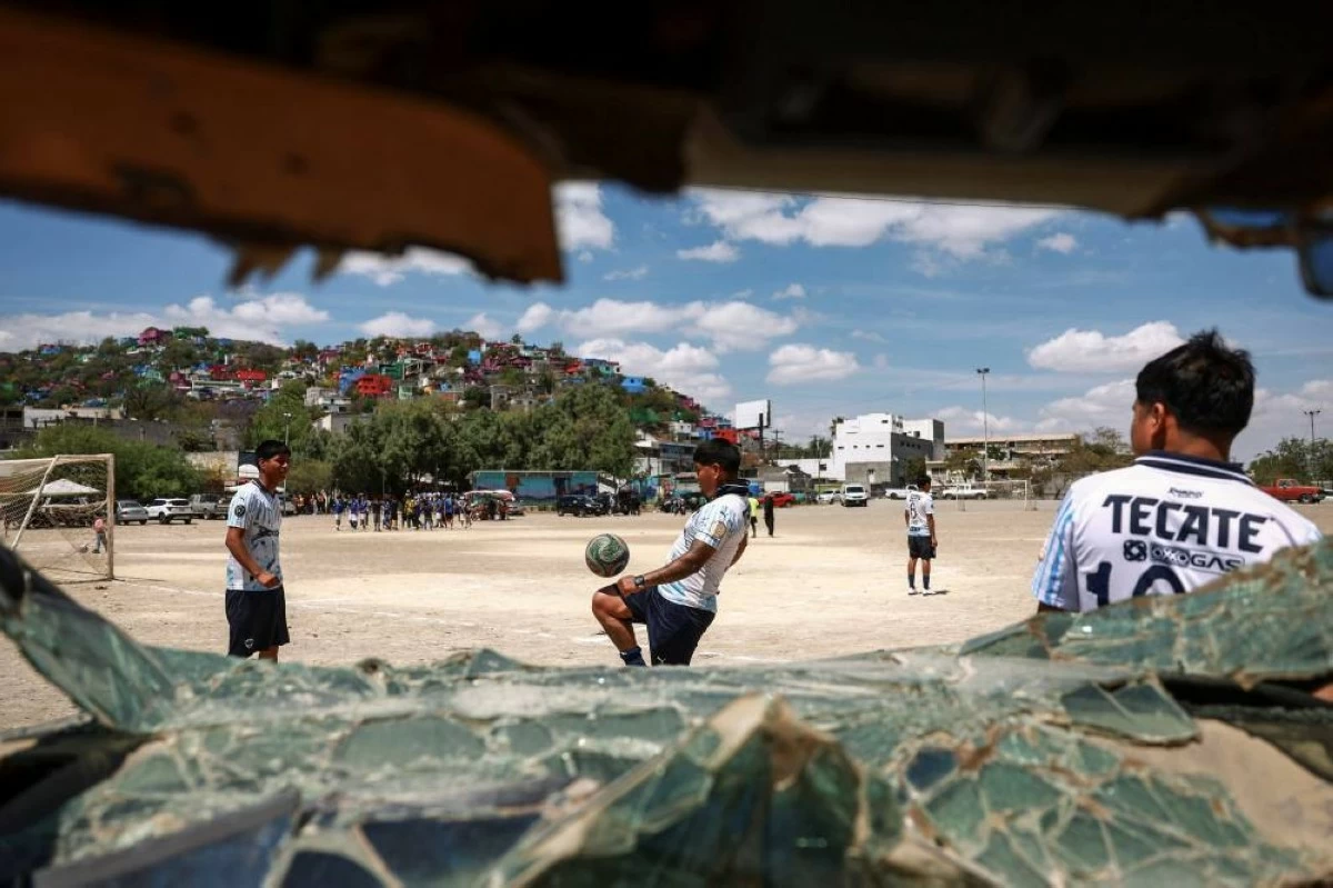 'Pandilleros' team members are seen warming up through a broken car window ahead of the Cerro de la Campana llanero soccer championship semifinal against 'Bandoleros' at Los Pinos football pitch in Monterrey, Mexico, March 29, 2026. REUTERS/Raquel Cunha   