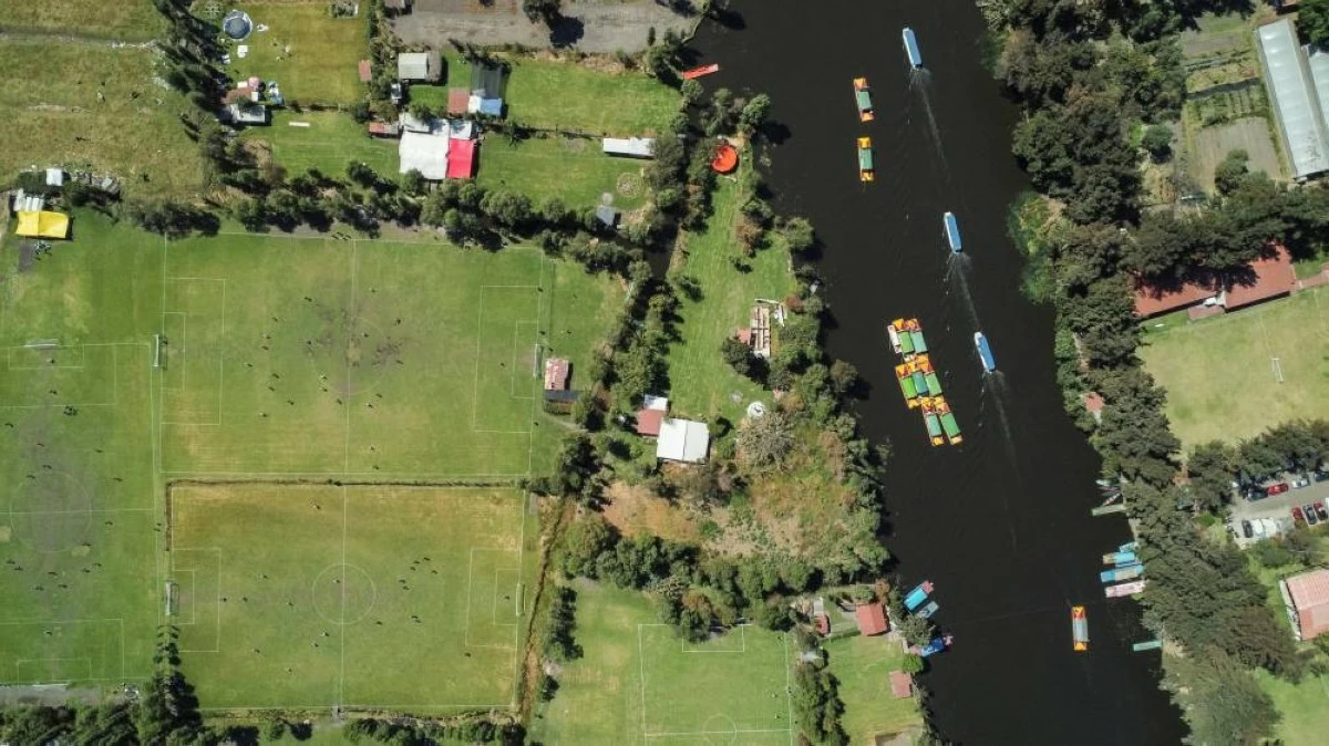 A drone view shows locals playing football at pitches as people ride boats and trajineras in the Xochimilco ecological zone, composed of water channels and chinampas, or so-called floating gardens, a reminder of traditional pre-Hispanic land use, in Mexico City, Mexico, March 1, 2026. REUTERS/Raquel Cunha   