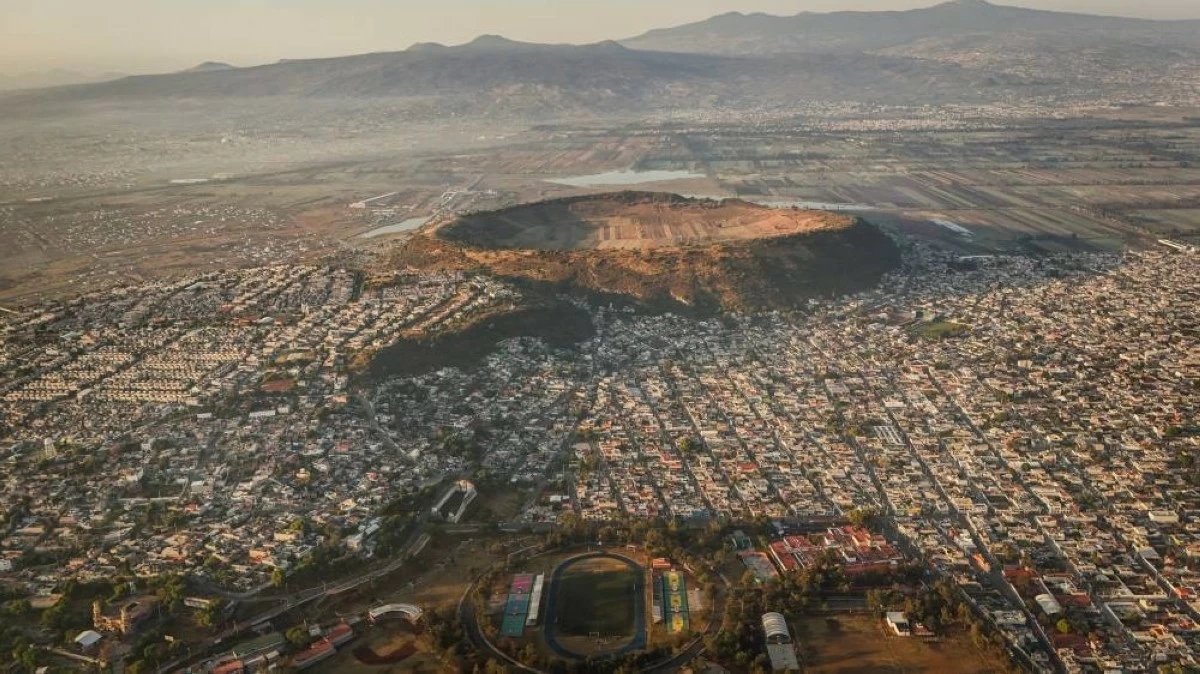 A drone view shows a soccer field at the Sports Unit "Luis Donaldo Colosio" with the crater of the Xico volcano, an almost perfectly circular tuff ring known locally as the "navel of the world", on the outskirts of Mexico City, Mexico, April 8, 2026. REUTERS/Raquel Cunha 
