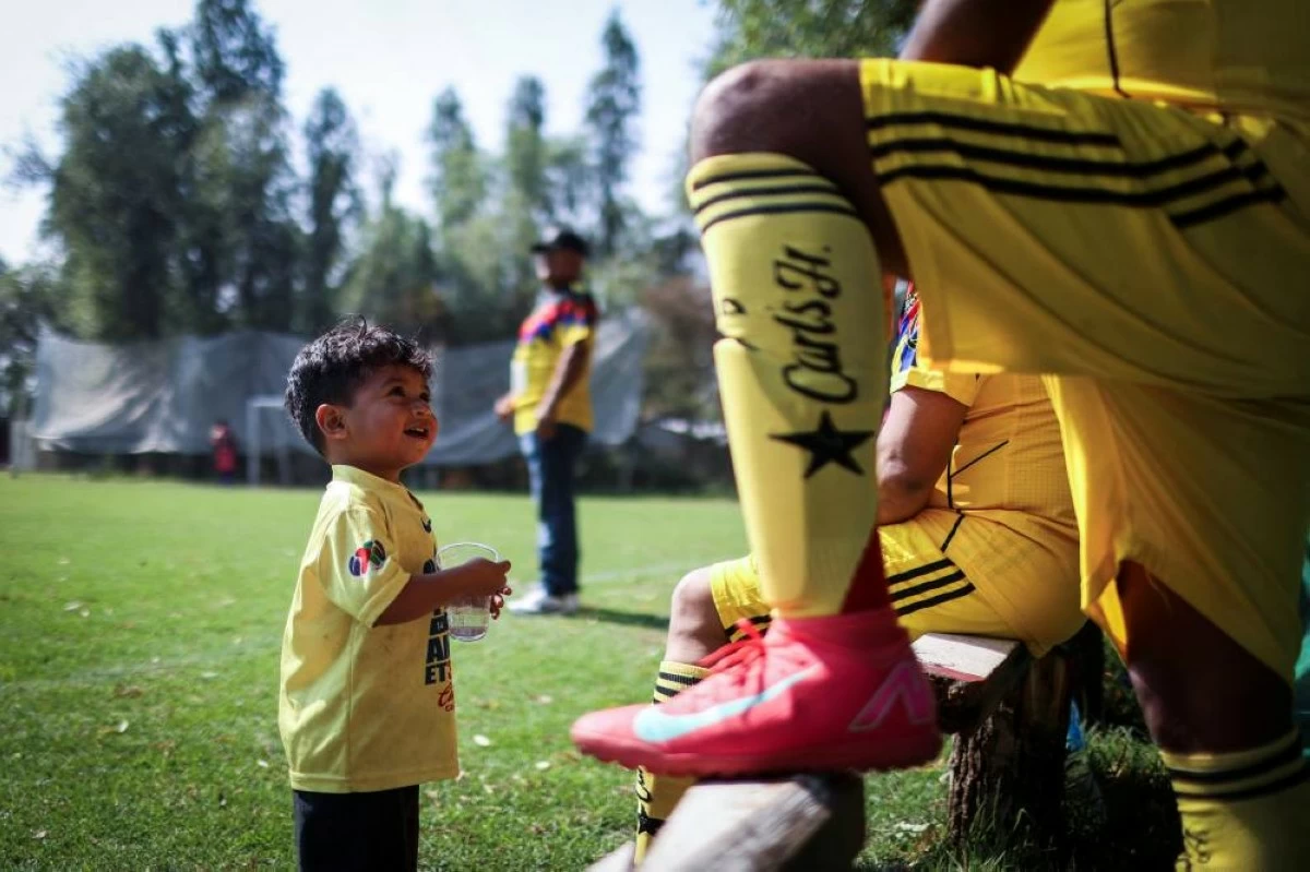 Emmanuel Dela Rosa, 2, looks at his father during an amateur league match between Real America and Mexico in the protected Xochimilco area, in southern Mexico City, Mexico, March 8, 2026. The UNESCO World Heritage site, known for its canals and chinampas, or so-called floating gardens, remains a social hub where residents gather for weekend football matches. REUTERS/Raquel Cunha  