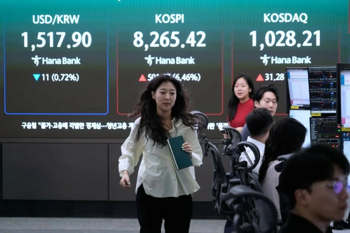 A currency trader passes by a screen showing the Korea Composite Stock Price Index (KOSPI) and the foreign exchange rate between U.S. dollar and South Korean won at the foreign exchange dealing room of the Hana Bank headquarters in Seoul, South Korea, Friday, June 12, 2026. (AP)