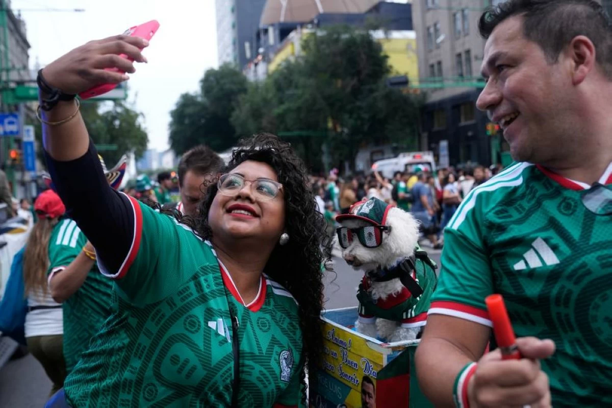 A fan, left, takes a photo with a dog named Osito, wearing a Mexico national soccer team jersey, next to Jorge Rangel before the World Cup Group A soccer match against South Korea in Mexico City, Thursday, June 18, 2026. (AP)