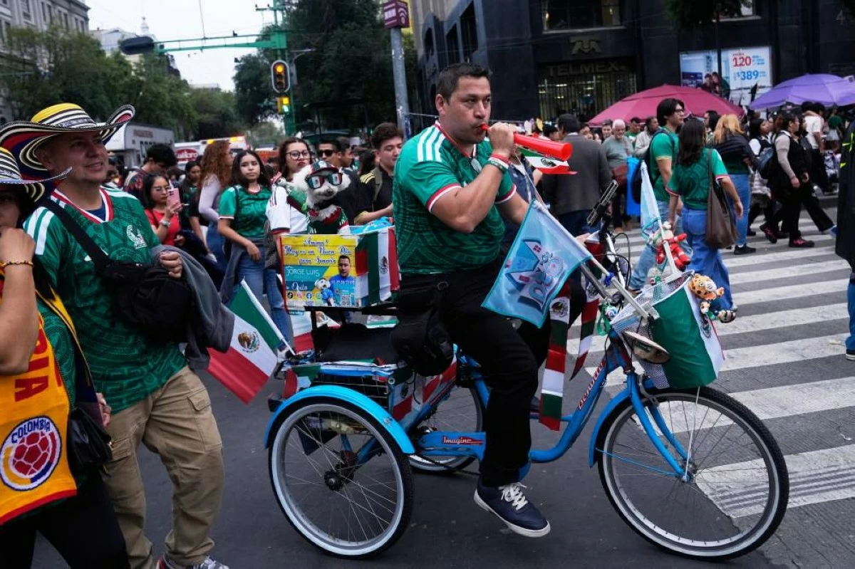 Jorge Rangel rides a bicycle accompanied by his dog, Osito, both wearing Mexico national team jerseys before their World Cup match against South Korea in Mexico City, Thursday, June 18, 2026. (AP)