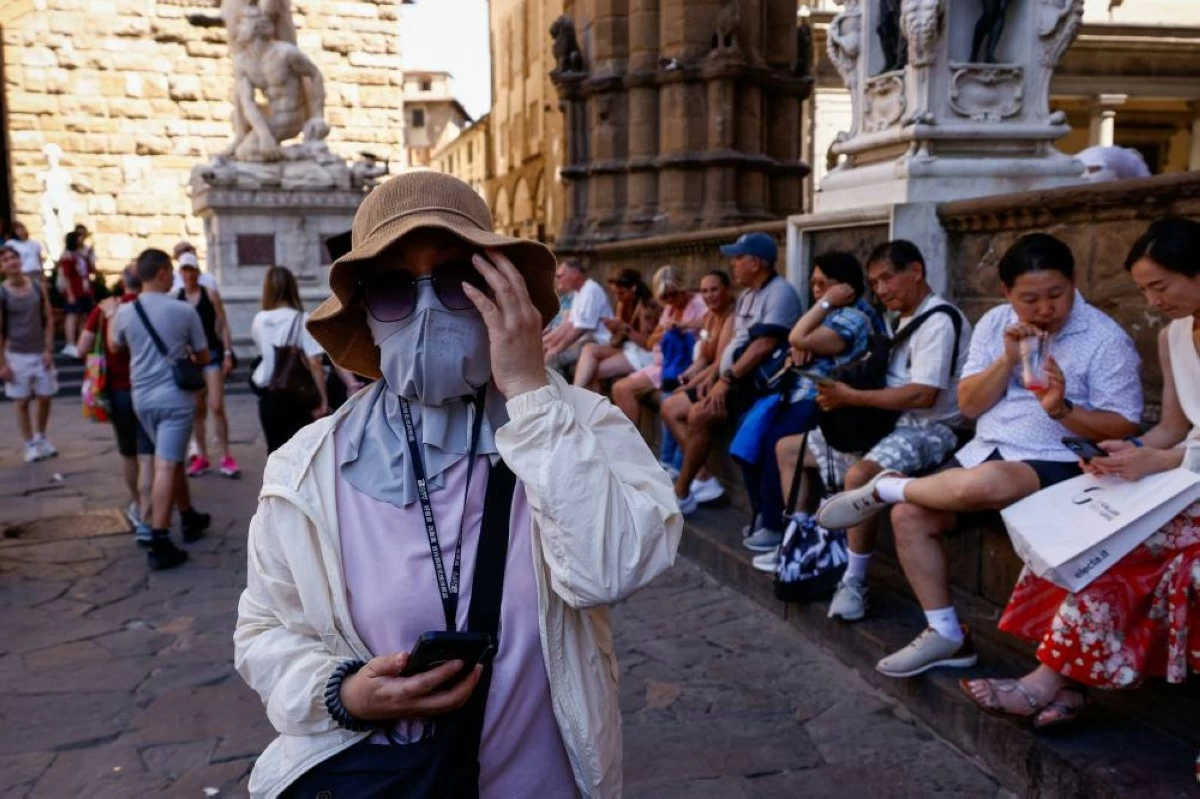 A tourist wears a hat and face covering to protect herself from the sun during a heatwave in Florence, Italy, June 19, 2026. REUTERS