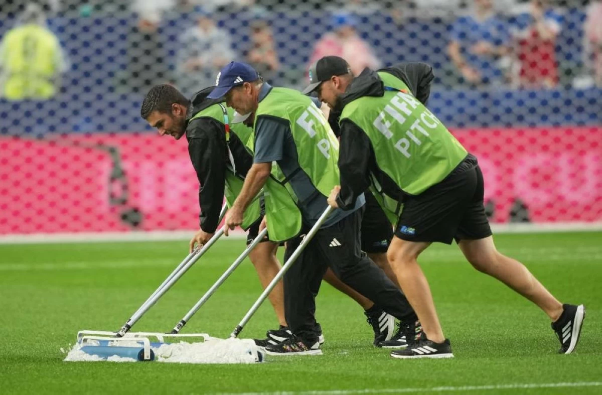 Groundskeepers work on the pitch as the match is delayed due to a thunderstorm warning. Picture credit: Reuters