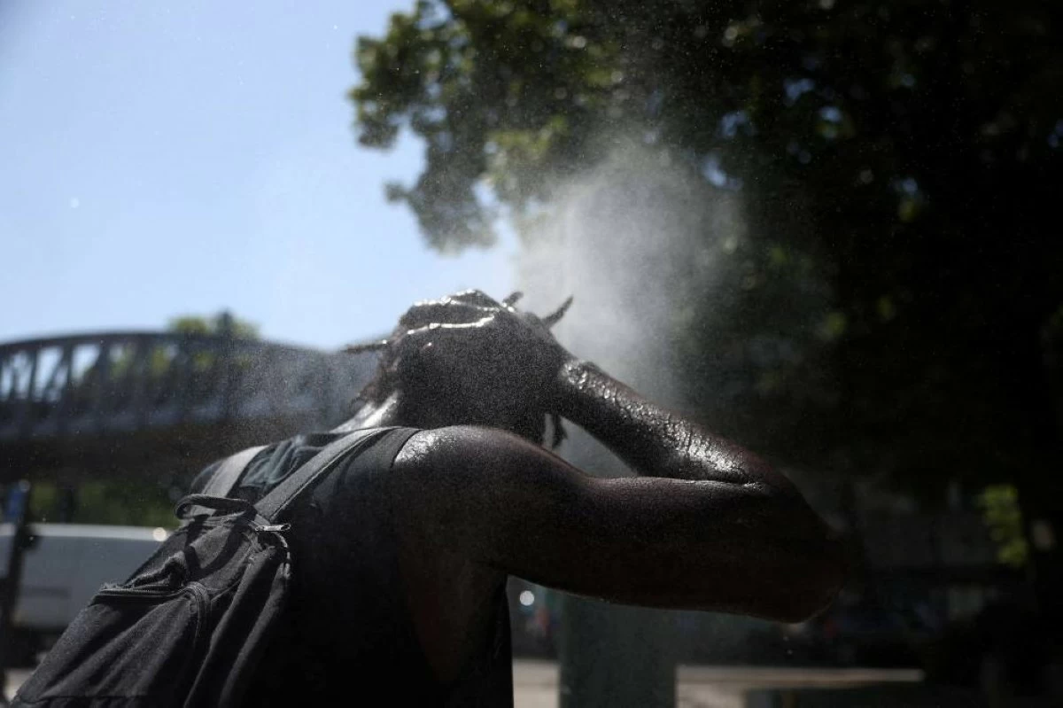 A person cools off at a water mister on a street in Paris. Reuters