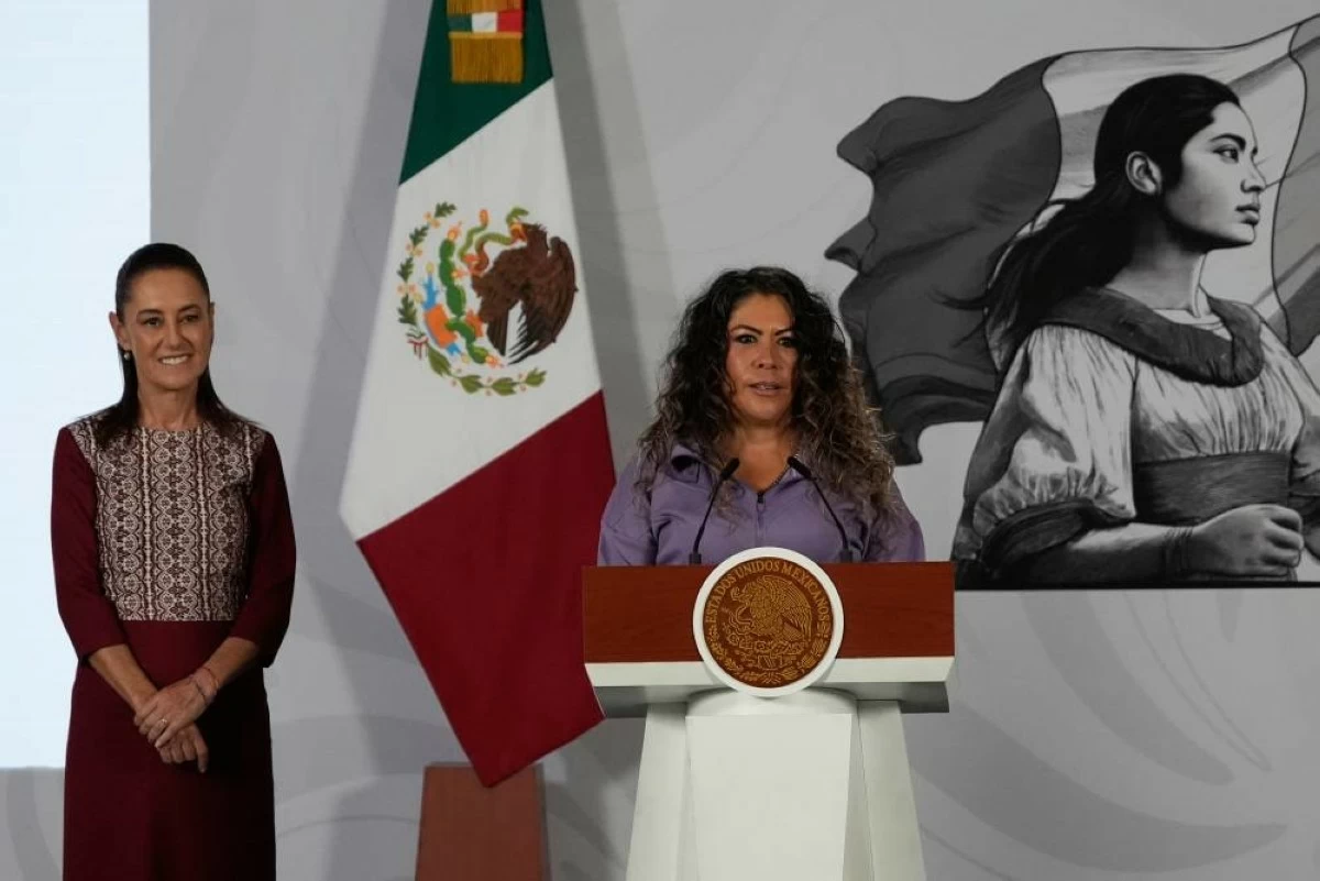 Carla Gomez, the caretaker of Merlin the duck, speaks during the daily press conference of Mexican President Claudia Sheinbaum, left, at the National Palace in Mexico City, Monday, June 22, 2026. (AP Photo/Marco Ugarte)