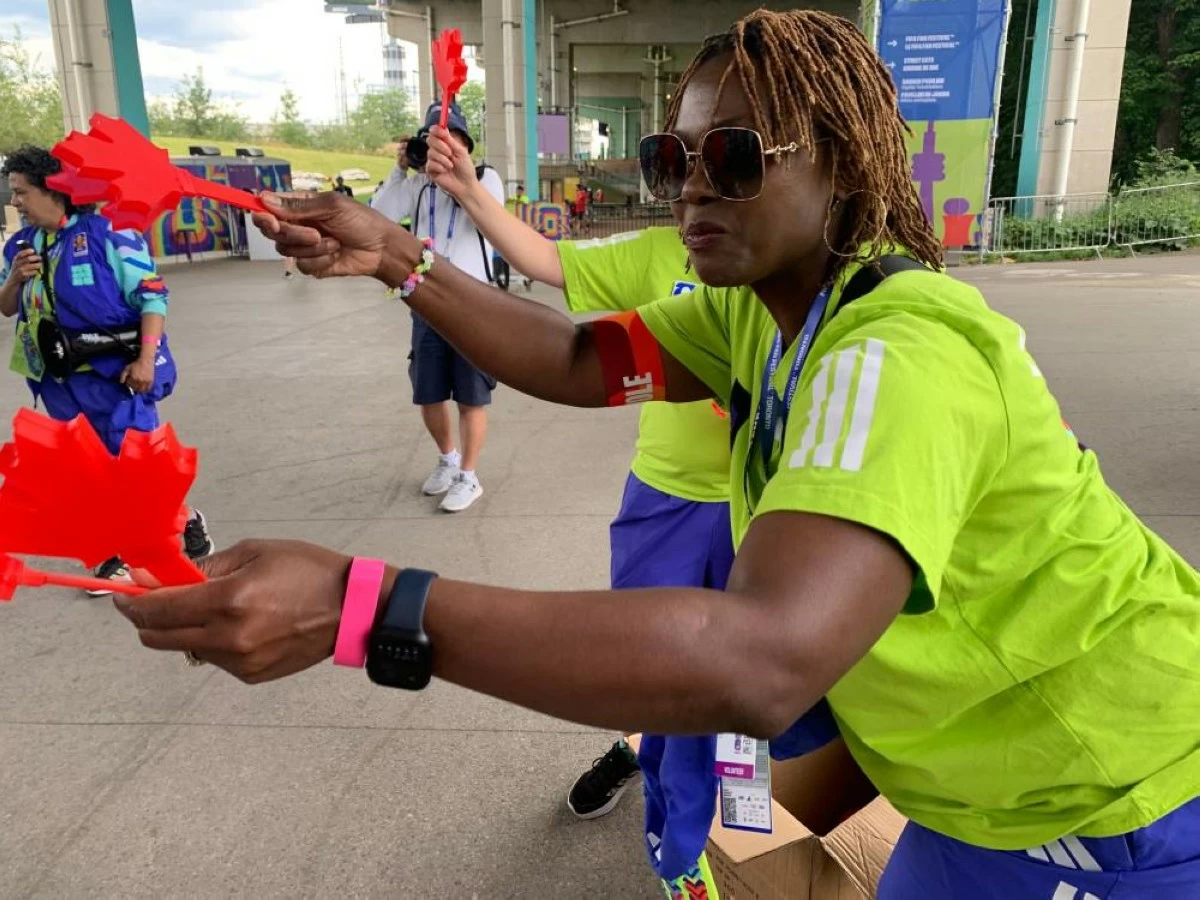 Volunteer Mbalu Lumor hands out "Canadian clappers" to attendees at the FIFA Fan Festival Wednesday, June 24, 2026, in Toronto. (AP Photo/Mike Householder)