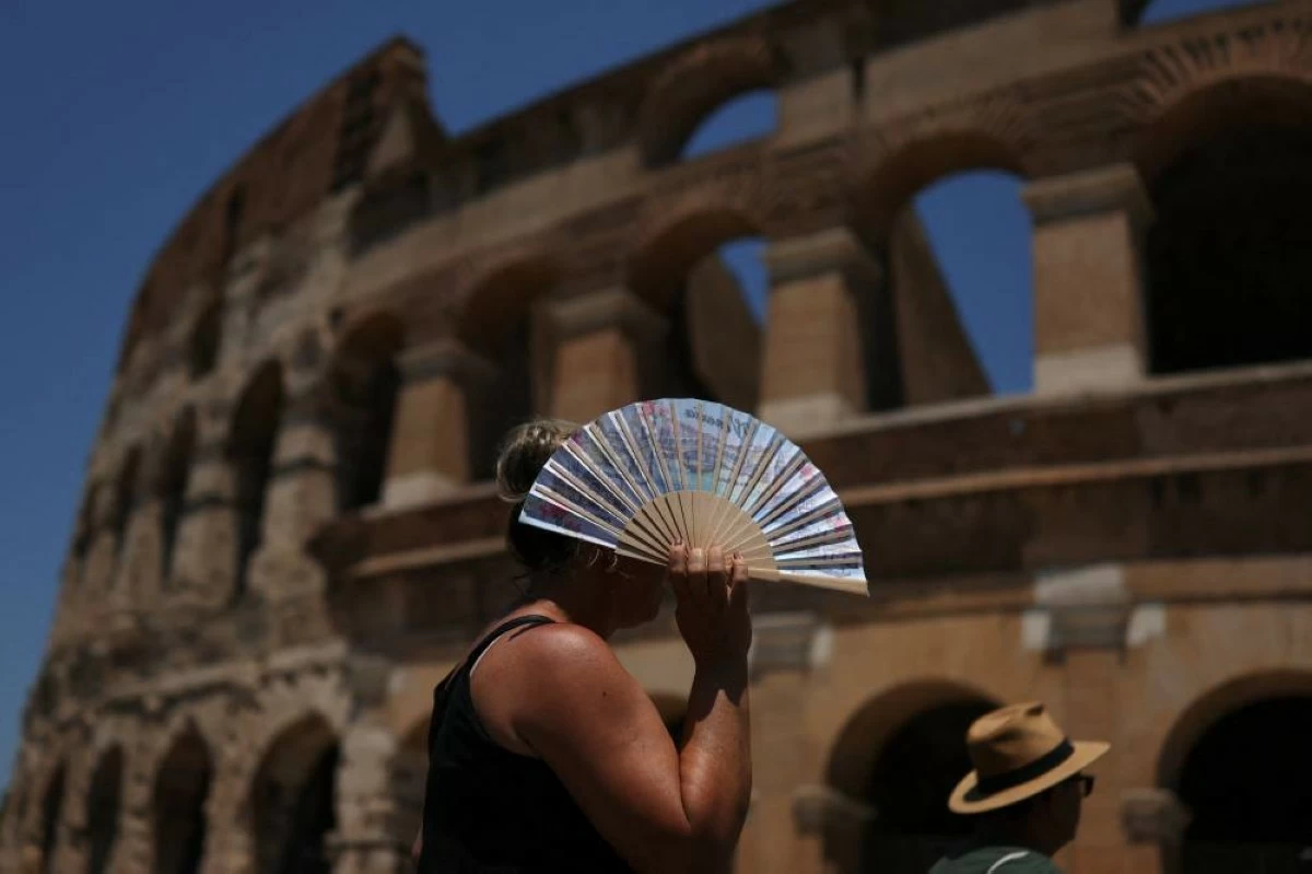 A woman uses a fan to shelter from the sun outside the Colosseum during a heatwave in Rome, Italy, June 28, 2026. REUTERS