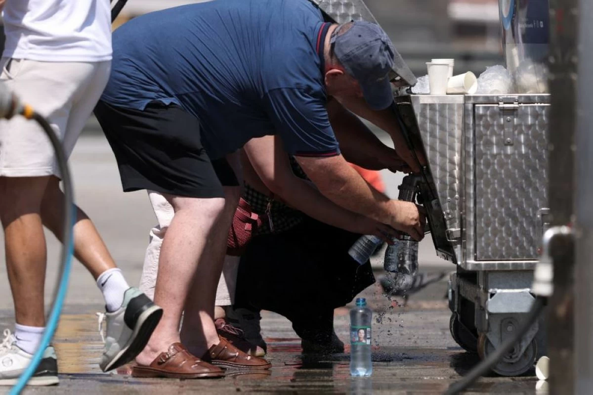 People fill bottles from a tanker providing free water, set up by the city due to the heatwave, in Warsaw, Poland, June 28, 2026. REUTERS