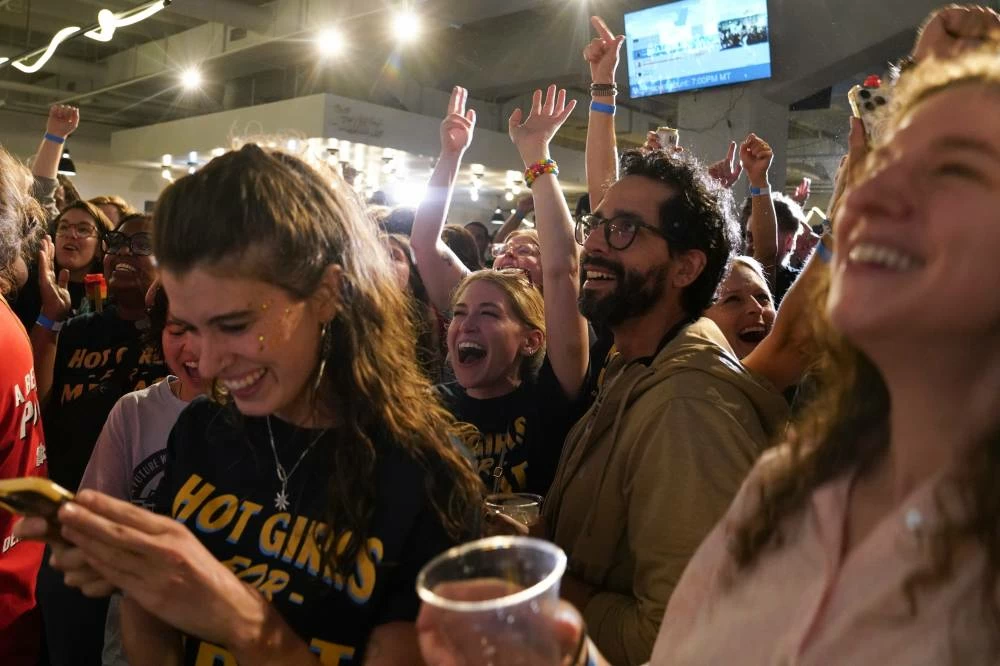 Supporters cheer as the second round of results come in with Democratic congressional candidate Melat Kiros leading during an election night watch party at The Broadway, Tuesday, June 30, 2026, in Denver. (AP Photo/Rebecca Slezak)