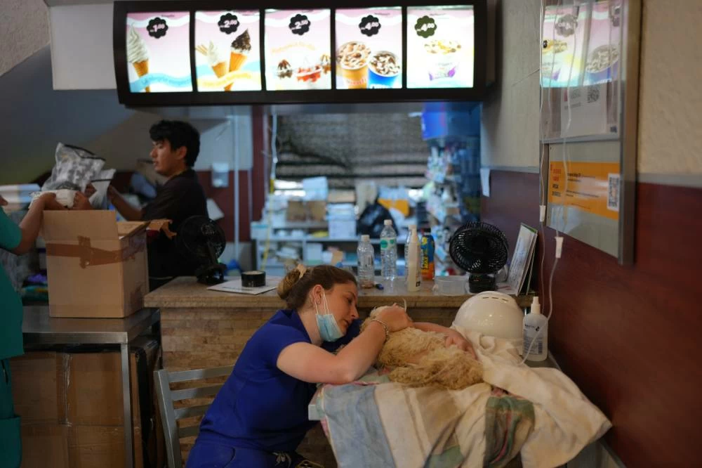 Gabriela Alves pets her dog, which she found alive in her apartment building a week after it was destroyed by the earthquakes that struck La Guaira, at a McDonald's restaurant being used as a temporary health center in La Guaira, Venezuela, Thursday, July 2, 2026. (AP)