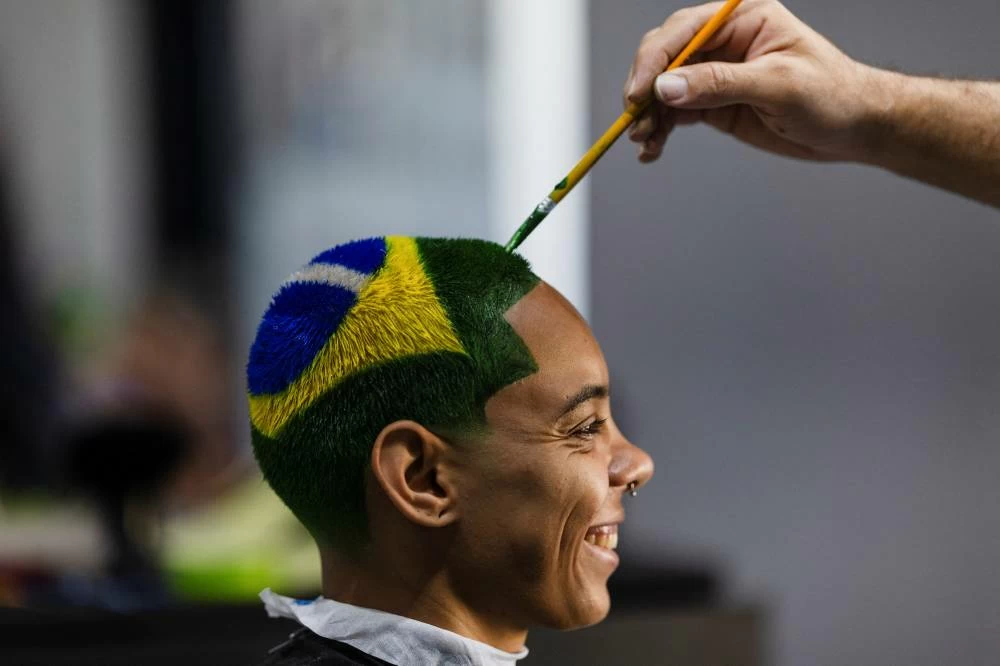 Barber Washington Rodrigo designs the Brazilian flag on Gleyziane Richely Souza's head as a hairstyle for the FIFA World Cup 2026 in Resende, Rio de Janeiro state, Brazil. Picture credit: Reuters