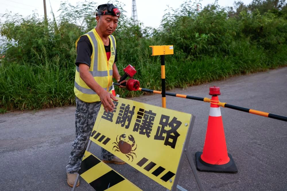 Volunteer Wu Ruei-chang, 60, a car mechanic, sets up a roadblock in Taijiang National Park in Tainan, Taiwan. REUTERS