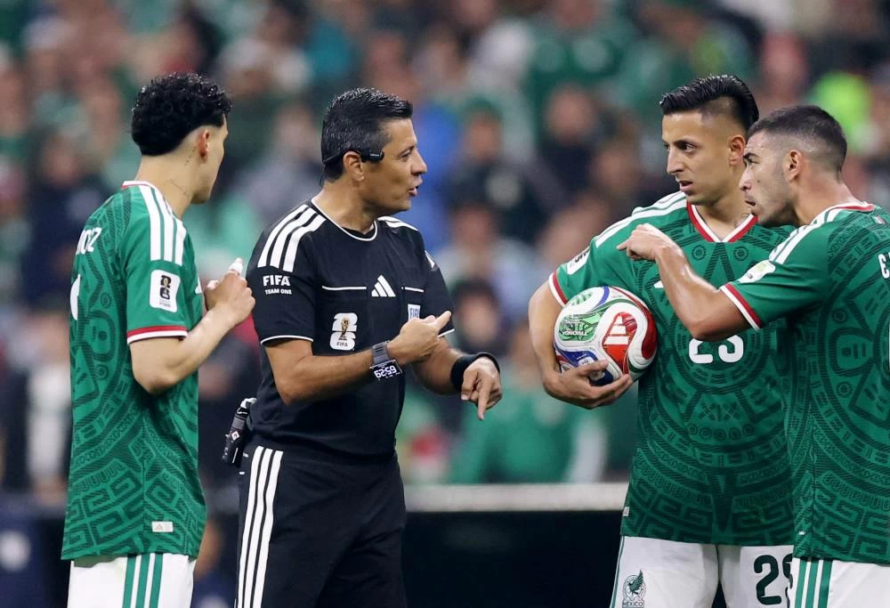Mexico players argue with referee Alireza Faghani as he refers to VAR for a potential penalty to Mexico. Picture credit: Reuters
