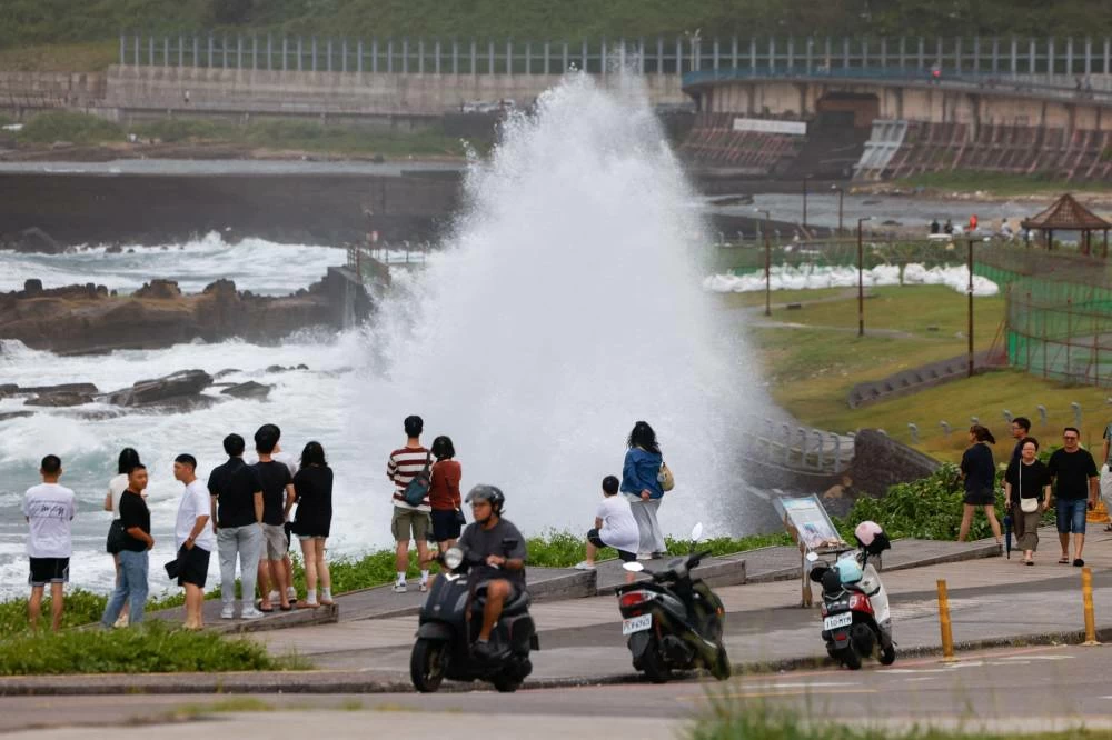 People watch waves crashing against the shoreline as Typhoon Bavi approaches in Keelung, Taiwan, July 10, 2026. REUTERS