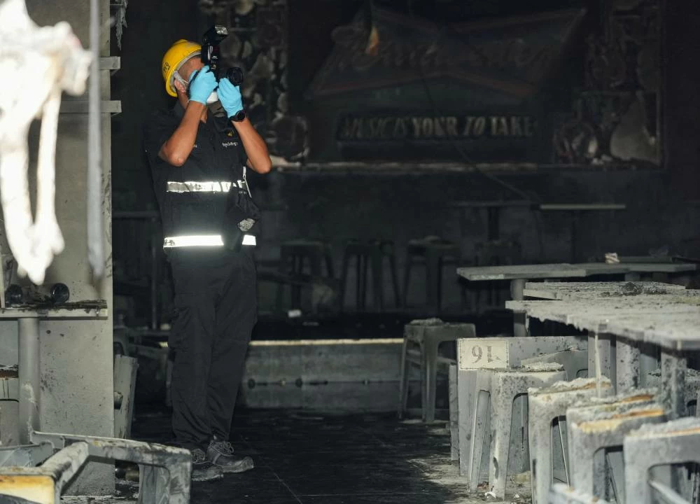 A forensic police official photographs the site of a deadly fire at a pub in Bangkok, Thailand, July 13, 2026. REUTERS