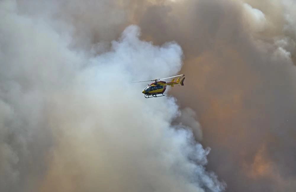 A fire fighting helicopter in action as wildfires are seen in the Fontainebleau forest region, about 60 kilometers (37 miles) south of Paris, France, Monday, July 13, 2026. (AP)