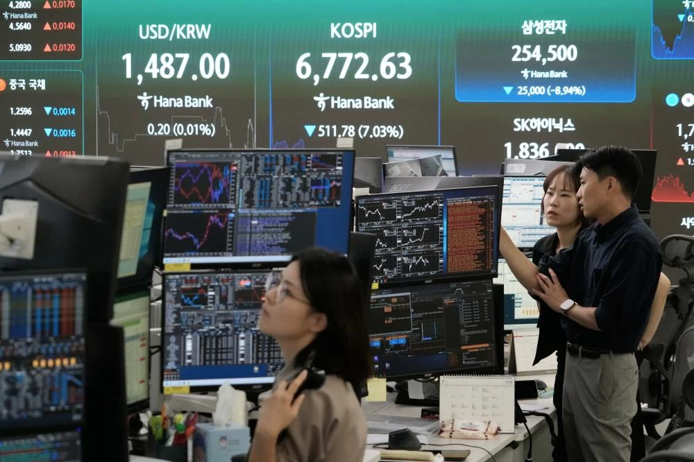 Currency traders work near a screen showing the Korea Composite Stock Price Index (KOSPI) and the foreign exchange rate between U.S. dollar and South Korean won at the foreign exchange dealing room of the Hana Bank headquarters in Seoul, South Korea, Thursday, July 16, 2026. AP
