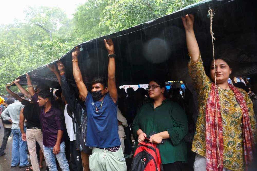Supporters of India's Cockroach Janta Party (CJP) take shelter under a sheet at a protest site during their protest at Jantar Mantar in New Delhi, India, July 22, 2026. (Reuters)