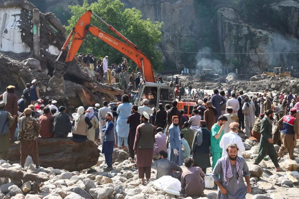 People gather as an excavator clears debris and searches through damaged areas following flash floods in Parun, the capital of Nuristan province, Afghanistan, July 21, 2026. (Reuters)