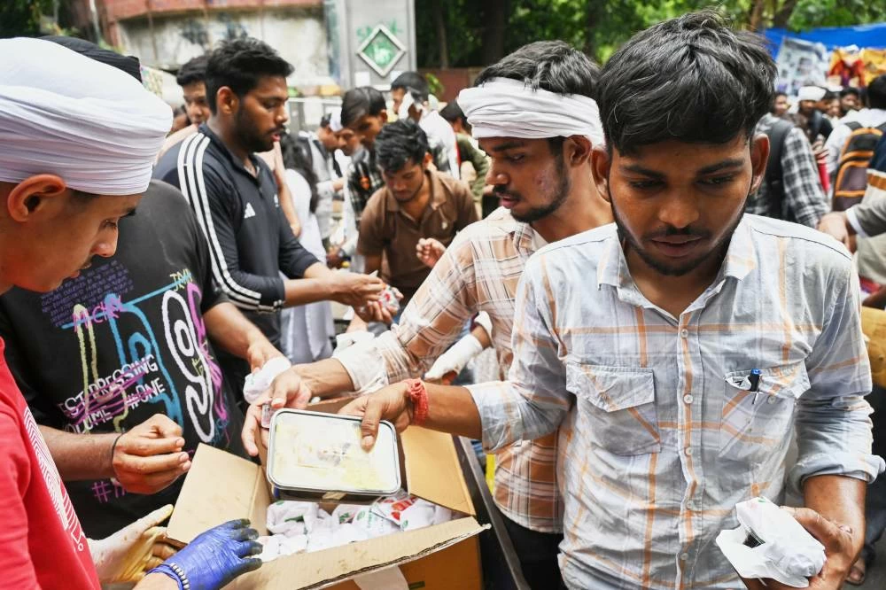 Volunteers distribute food received from supporters to protestors during a demonstration demanding educational reforms as part of the Cockroach Janta Party's ongoing protest movement in New Delhi, India, Thursday, July 23, 2026. (AP)