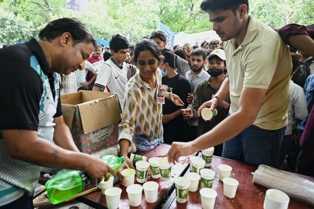 Volunteers distribute beverages received from supporters to protestors during a demonstration demanding educational reforms as part of the Cockroach Janta Party's ongoing protest movement in New Delhi, India, Thursday, July 23, 2026. (AP)