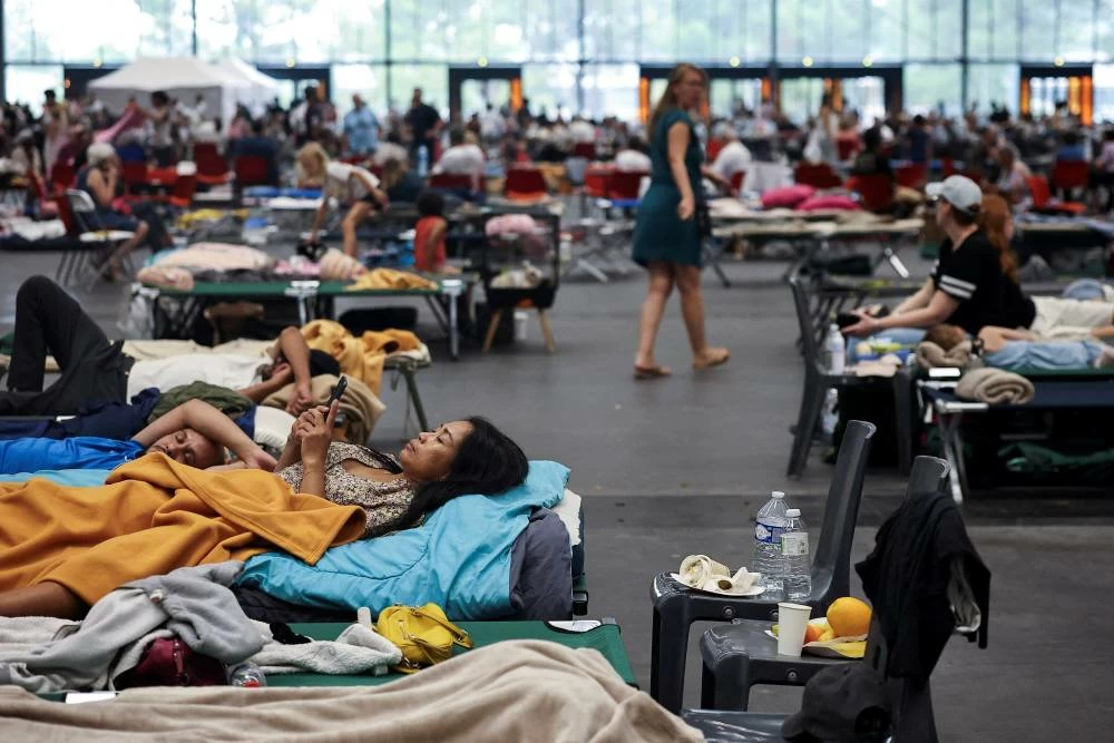 A woman looks at her phone at the Bordeaux-Lac Exhibition Centre, which has been turned into a shelter for people displaced by a wildfire burning nearby amid worsening drought conditions following a heatwave and water shortages across much of France, in Bordeaux, France, July 25, 2026. REUTERS