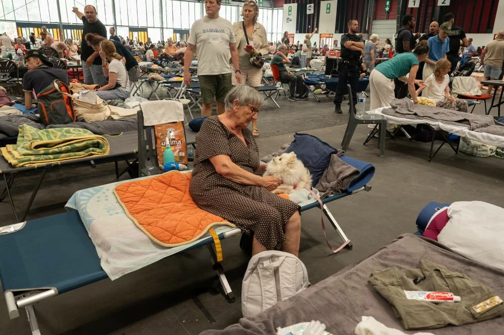 An elderly woman caresses her pet dog at an emergency shelter set up in the Bordeaux Exhibition Centre in Bordeaux, France. AP