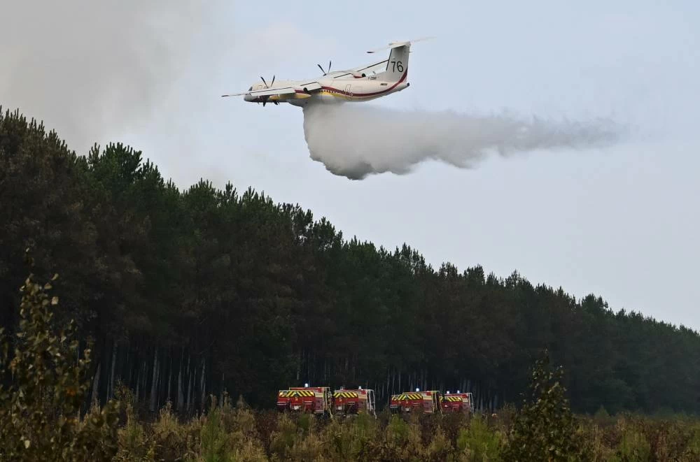 A De Havilland Canada DHC-8-400 Dash 8 operated by the French civil defense agency drops fire retardant as wildfires rage near Le Las, outside Bordeaux, France, Monday, July 27, 2026. AP