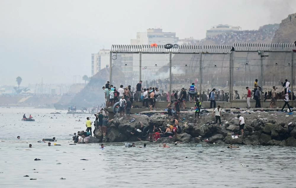 Migrants from Morocco gather by the border fence as they cross the Spanish border, swimming through the sea, as seen from Ceuta, Spain, July 31, 2026 (Reuters)