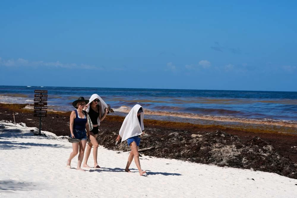 Tourists walk at a beach covered with sargassum in Tulum, Mexico, Thursday, July 30, 2026. (AP)