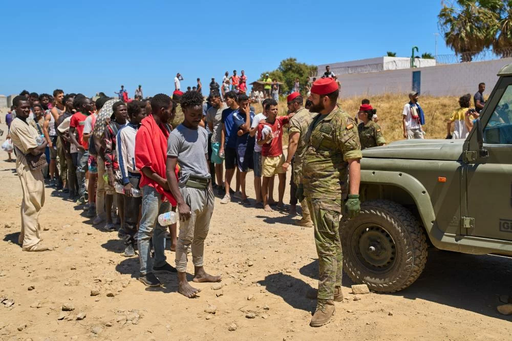 Migrants line up for water distributed by Spanish soldiers in the Spanish enclave of Ceuta, Sunday, Aug. 2, 2026. (AP)