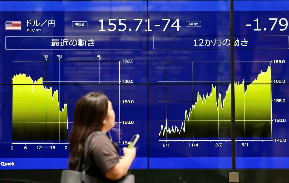 File picture of a woman in front of an electronic screen displaying graphs showing the current and recent Japanese Yen exchange rate against the U.S. dollar. The yen was trading at 157.8 per US dollar, down 0.4% on the day. However, it remained significantly stronger than the 40-year low of 163.99 per dollar reached in July and well above Monday's three-month high of 155.20. REUTERS