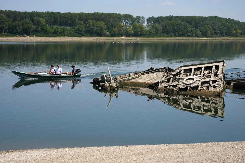 People watch the wreckage of a WWII German warship, emerged due to the drought, in front of Djerdap II, a large dam on the Danube River, between Romania and Serbia, near Prahovo, Serbia. Picture credit: AP