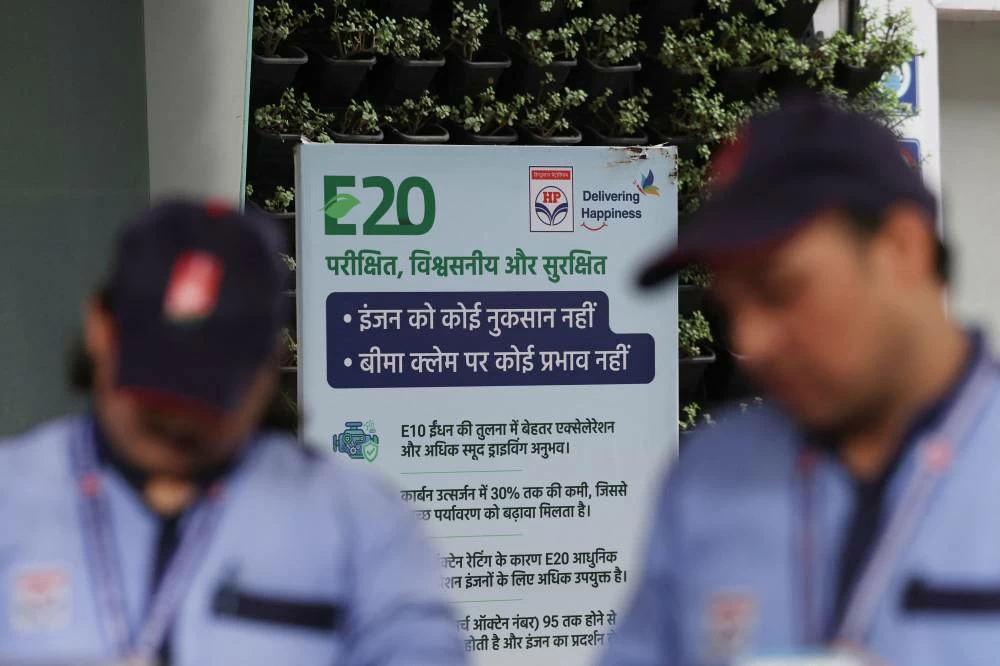 Workers stand near a signboard with information on E20 petrol at a Hindustan Petroleum fuel station in New Delhi, India, August 3, 2026. (Reuters)