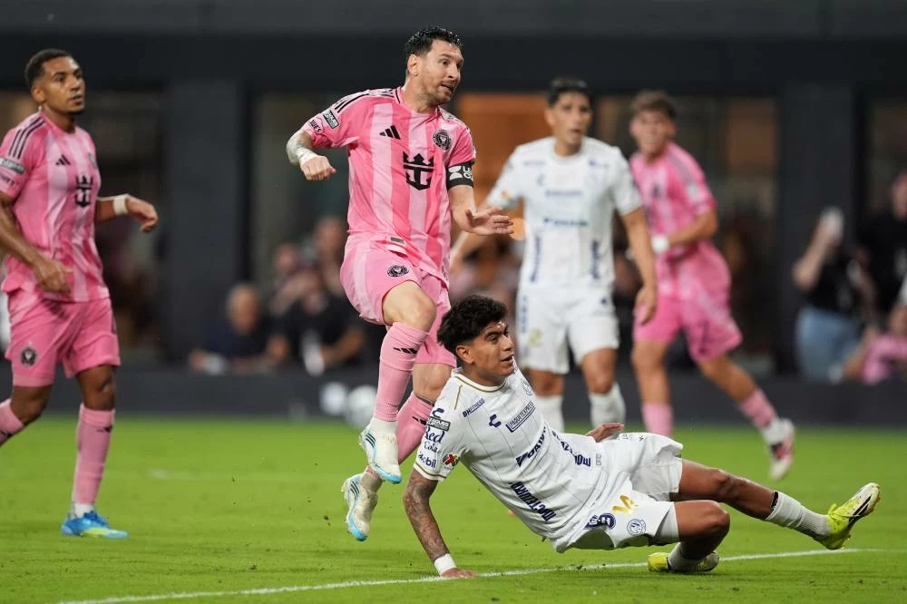 Inter Miami forward Lionel Messi, top, watches his ball as he scores his side's third goal past Atletico de San Luis midfielder Miguel Garcia (14) during the first half of a Leagues Cup soccer match against Atletico de San Luis, Wednesday, Aug. 5, 2026, in Miami. (AP)