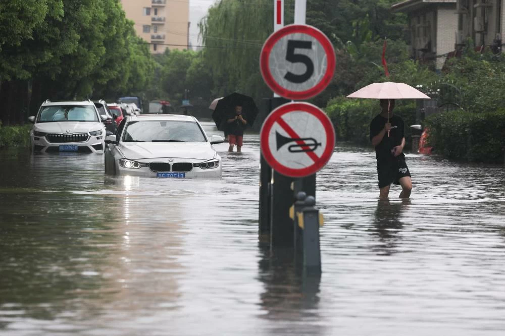 People wade through a flooded street after Typhoon Dolphin brought heavy rain to Shanghai, China, August 10, 2026. REUTERS