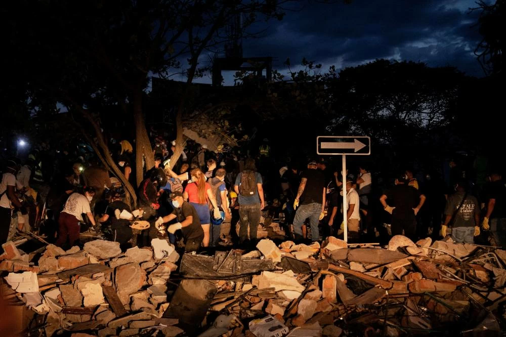 People dig through debris at the site of a collapsed building as recovery efforts continue at night following an earthquake, in Cali, Colombia August 10, 2026. (Reuters)