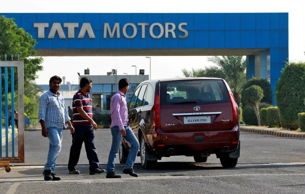 A vehicle drives past three men walking out of a Tata Motors car plant at Sanand in the western Indian state of Gujarat, India, October 27, 2016. (Reuters)