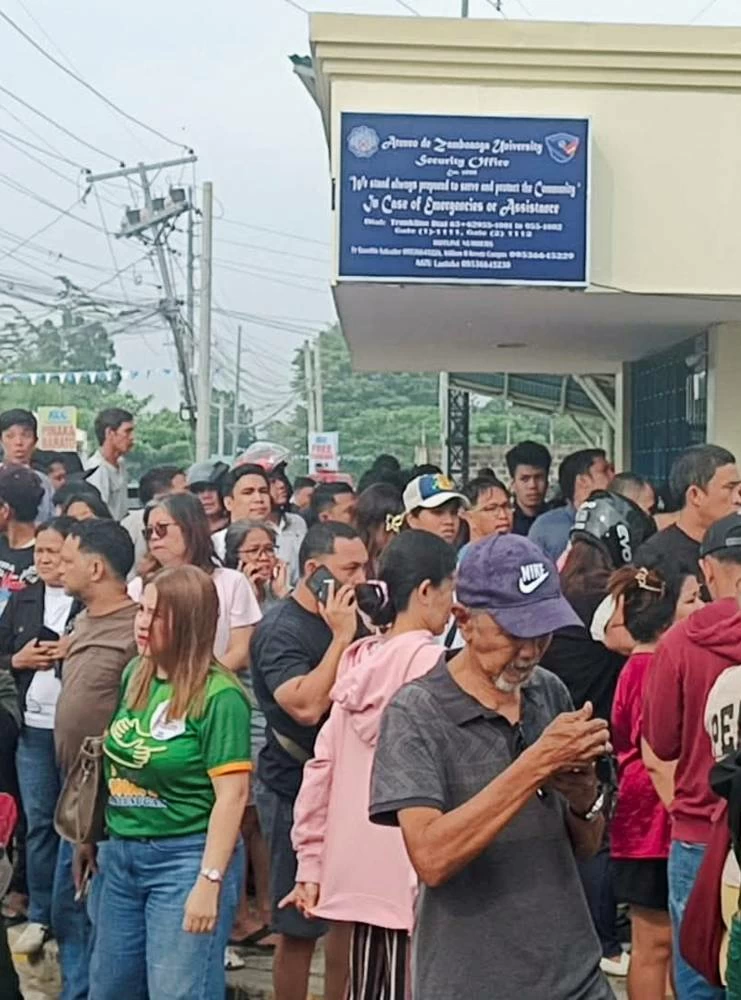 People stand outside Ateneo de Zamboanga University after a shooting that killed two people, in Zamboanga, southern Philippines, August 18, 2026. (Reuters)