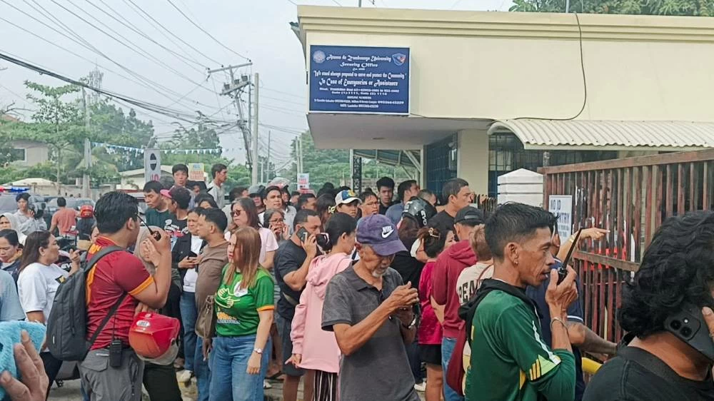People stand outside Ateneo de Zamboanga University after a shooting that killed two people, in Zamboanga, southern Philippines, August 18, 2026. (Reuters)