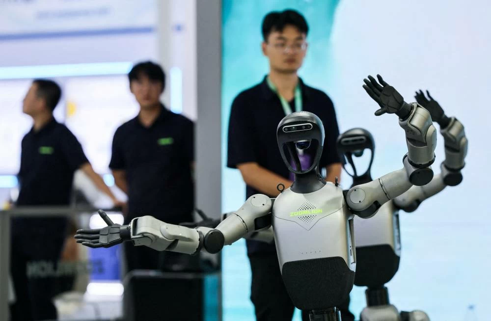 Company employees look on next to dancing humanoid robots at the Zoomlion booth the 2026 World Robot Conference, in Beijing, China, August 19, 2026. (Reuters)