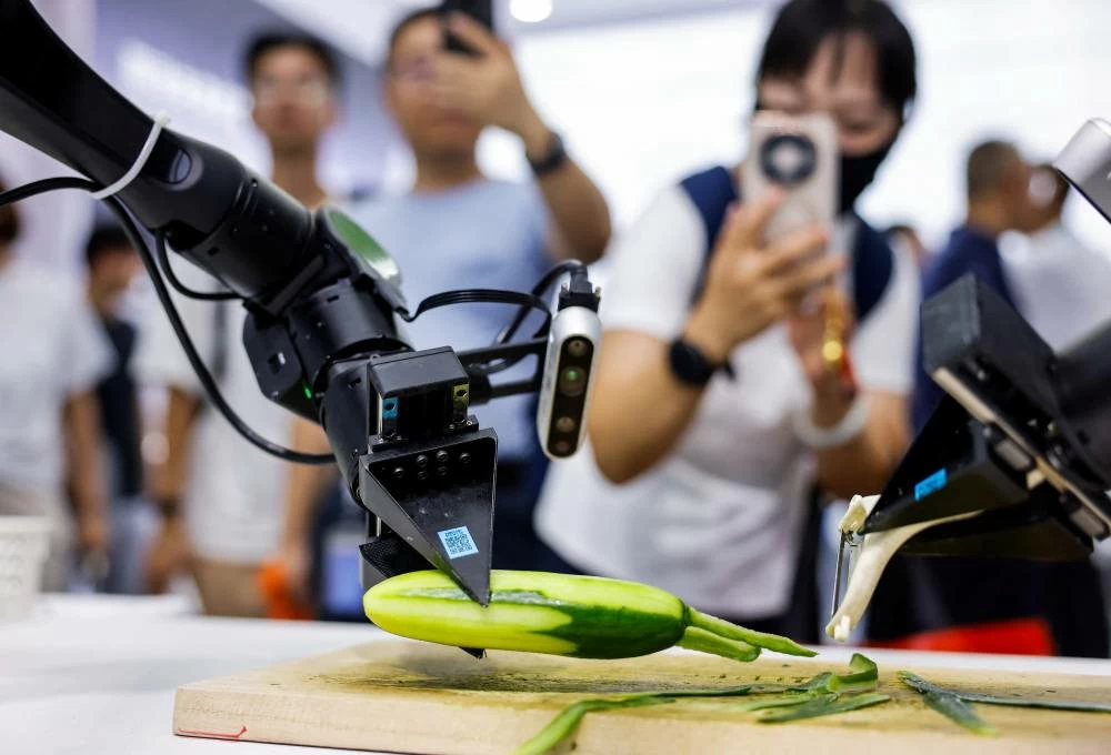 People take images of robotic arms peeling a cucumber at the Dexmal booth at the 2026 World Robot Conference, in Beijing, China, August 19, 2026. (Reuters)