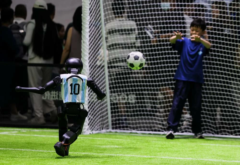 A Booster Robotics humanoid robot plays soccer with a boy at the company’s booth at the 2026 World Robot Conference, in Beijing, China, August 19, 2026. (Reuters)