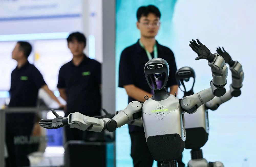 Company employees look on next to dancing humanoid robots at the Zoomlion booth the 2026 World Robot Conference, in Beijing, China, August 19, 2026. (Reuters)