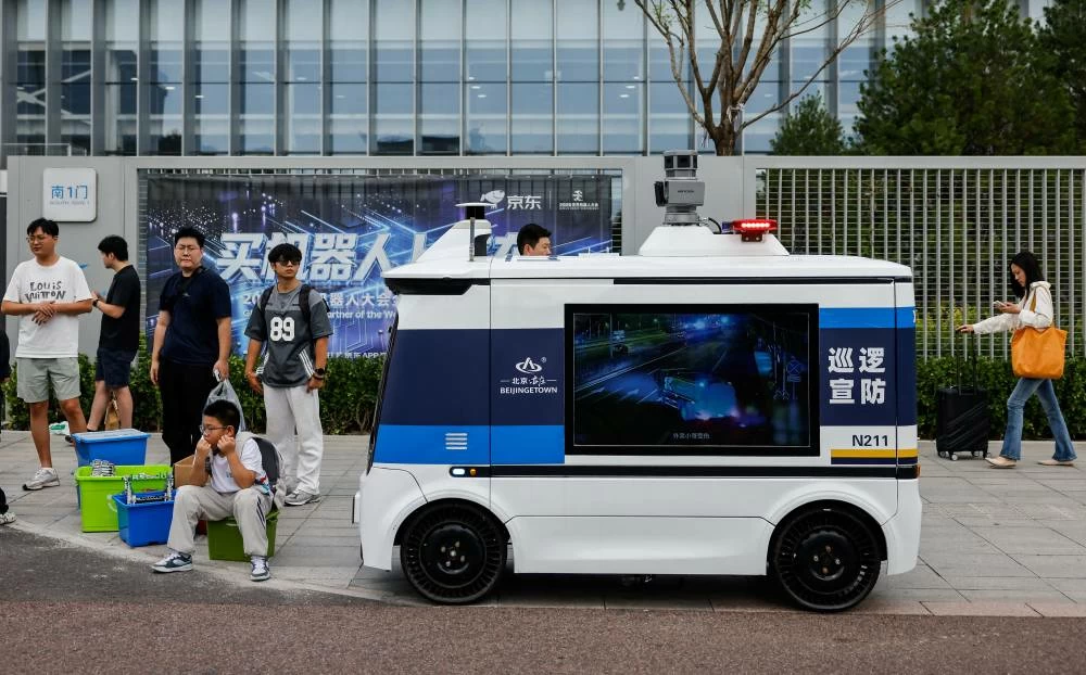 People gather next to an autonomous police vehicle next to the entrance to the 2026 World Robot Conference, in Beijing, China, August 19, 2026. (Reuters)