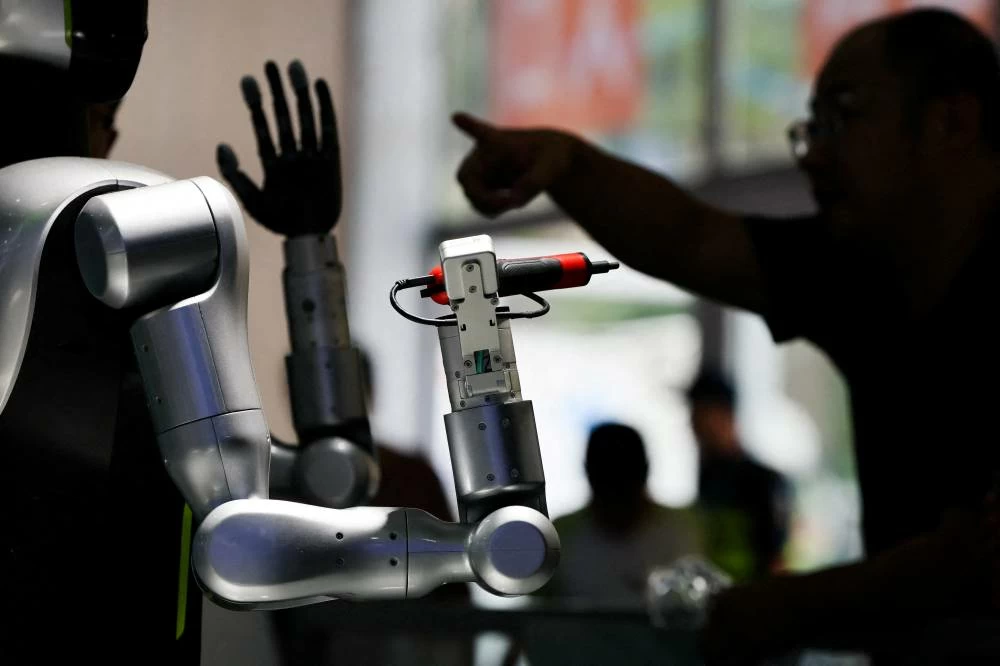 A man gestures next to a humanoid robot at the Zoomlion booth at the 2026 World Robot Conference, in Beijing, China, August 19, 2026. (Reuters)