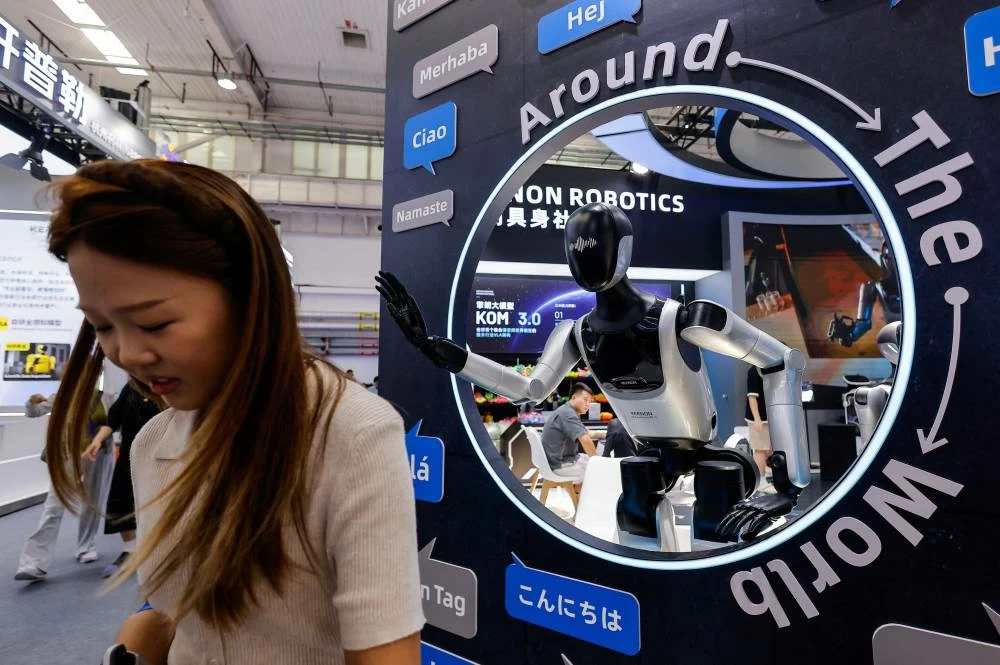 A woman passes by humanoid robots on display at the Keenon Robotics booth at the 2026 World Robot Conference, in Beijing, China, August 19, 2026. (Reuters)